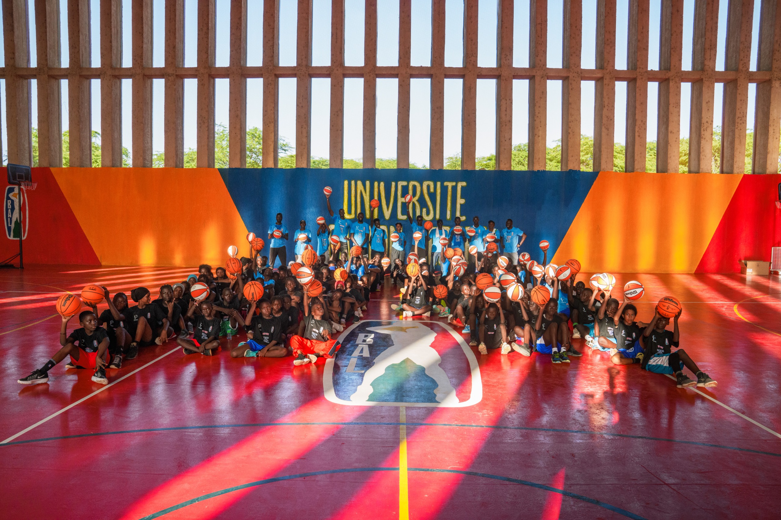 Jeunes basketteurs posant avec des ballons sur un terrains rénové par la Basketball Africa League(BAL)