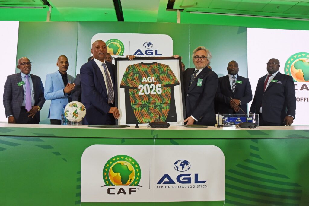 Des représentants de la CAF et d’AGL présentent un maillot AGL 2026 lors de la signature du partenariat logistique
