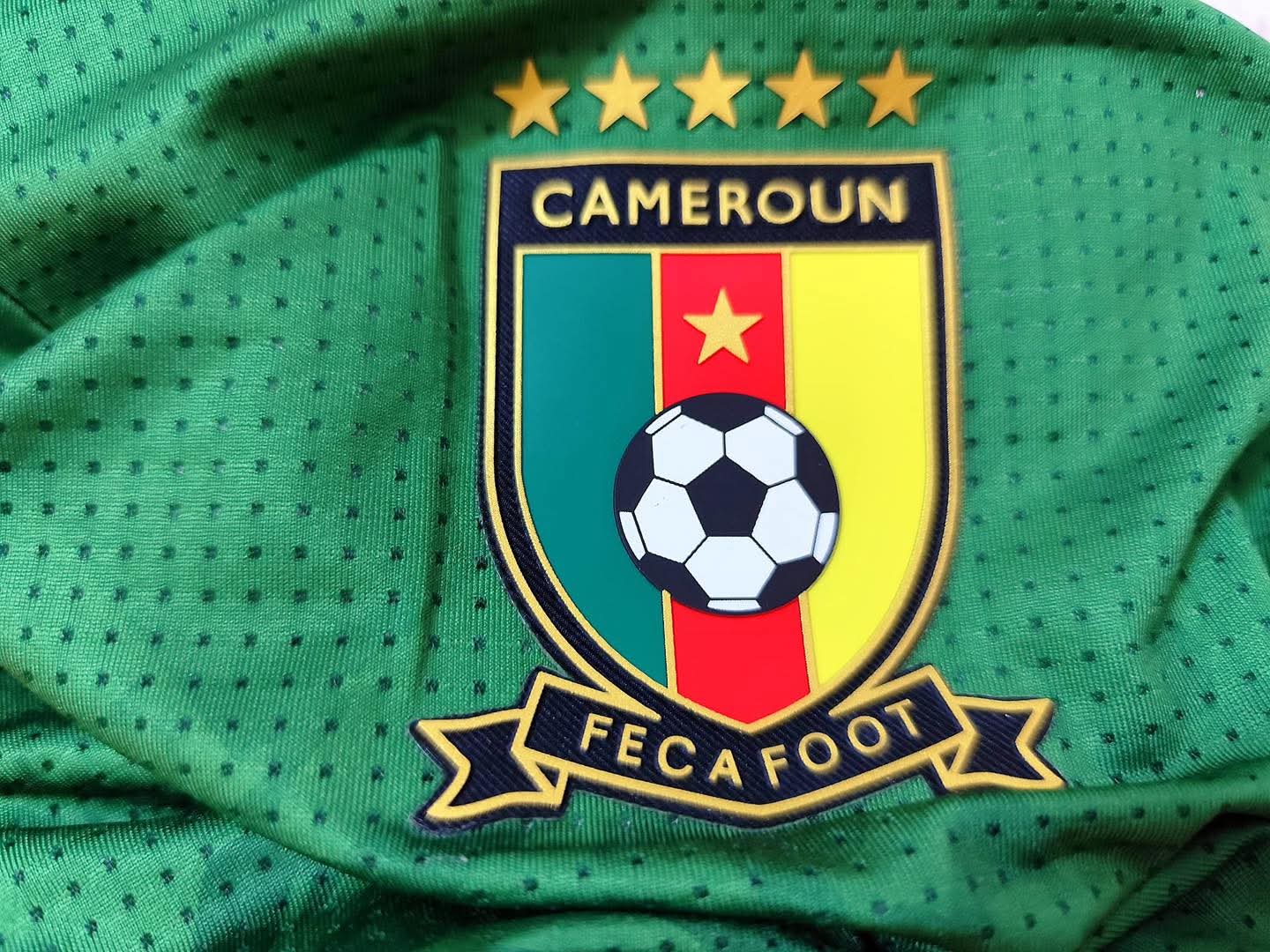 Écusson de la FECAFOOT sur le maillot vert de l’équipe nationale du Cameroun.
