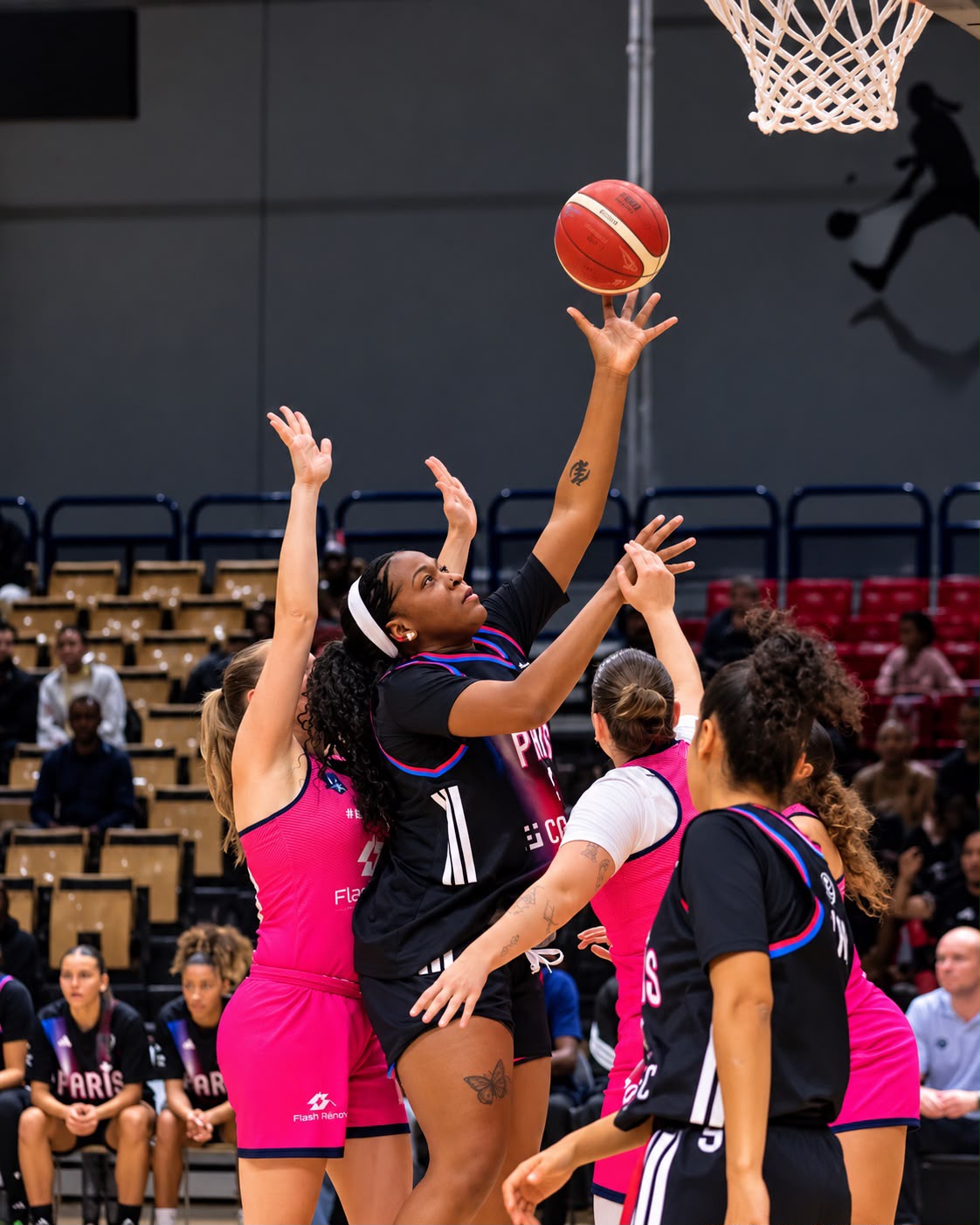 Hermine Ngueko, pivot camerounaise du Paris Basketball féminin, tente un tir près du panier face à la défense adverse.