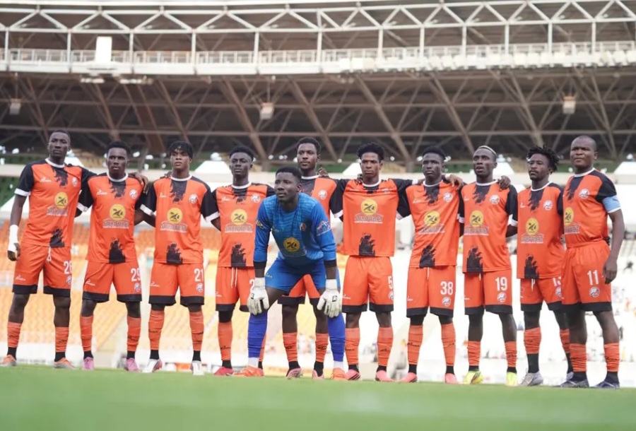 Joueurs du FC San Pedro en maillot orange et noir réunis sur le terrain avant un match.
 